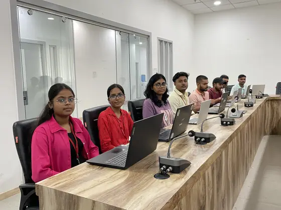 Students working at laptops around the bench in the SSS training room