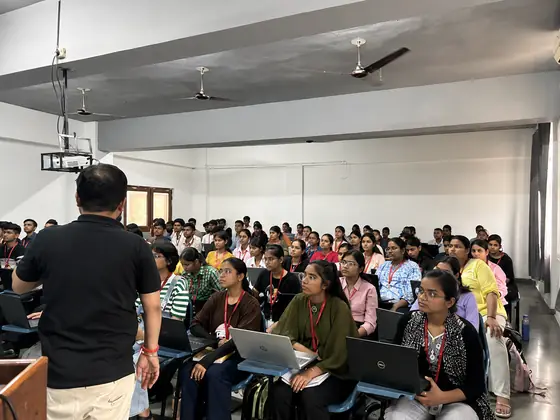 A SSS trainer facing rows of students, several of them following along on laptops
